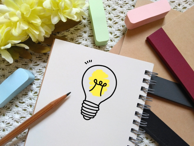 電球のイラストが描かれたノートと鉛筆